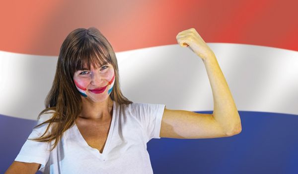 一名脸上画着杜特旗的妇女在一面荷兰国旗前弯曲
