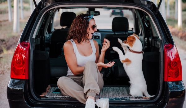 一个女人和她的狗在她拥有的一辆车的后备箱